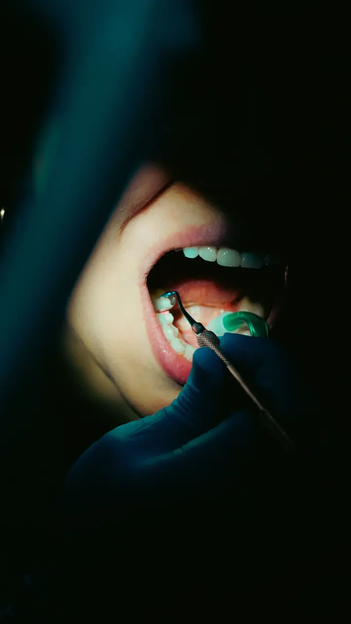 A dentist examining a patient with a mirror under focused light